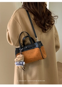 Dettaglio di una borsa Kelly bicolore minimalista con ciondolo a orso e tracolla