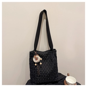 Close-up of black quilted tote bag with a soft sheep charm and wide shoulder strap