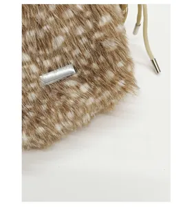 Detail einer Kunstfell-Beuteltasche mit silberner Plakette und gewebtem Kordelzug