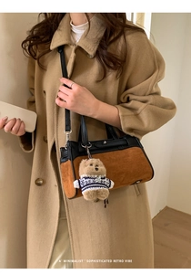 Dettaglio della borsa in pelle a contrasto con un ciondolo a forma di cane di peluche