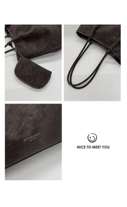 Detail view of dark brown leather tote bag with white stitching and hanging pouch accessory