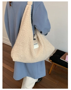 Close-up of off-white faux shearling tote bag featuring EEYOU side label and plush texture