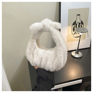 Detail of white faux fur handbag featuring a stylish knotted handle and plush texture