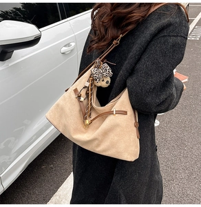 Detail of khaki suede dumpling bag featuring leopard bear pendant and tassel accessories