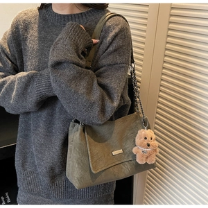 Olivgrüne Schultertasche aus Wildleder mit Kettenriemen und braunem Plüsch-Anhänger