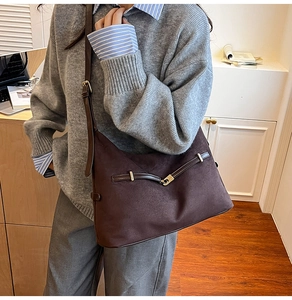 Close-up of brown suede shoulder bag with gold buckle and leather trim details