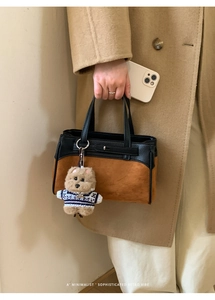 Dettaglio della borsa Kelly minimalista in pelle con ciondolo a forma di orsetto peluche