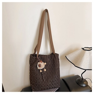 Detailed close-up of dark brown quilted tote bag with soft plush sheep charm accessory