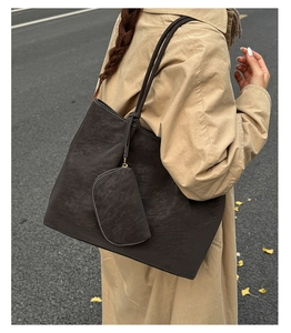 Detail of vintage matte tote bag with small coin purse on a beige trench coat