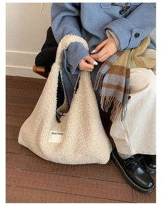Detail of off-white faux shearling tote bag with SEEYOU label on a cozy autumn outfit
