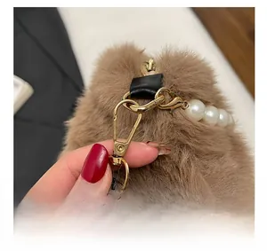 Gros plan d'une boucle en métal doré avec perles blanches sur sac en peluche marron