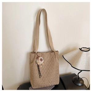 Detail of khaki quilted tote bag featuring diamond stitching and plush lion pendant