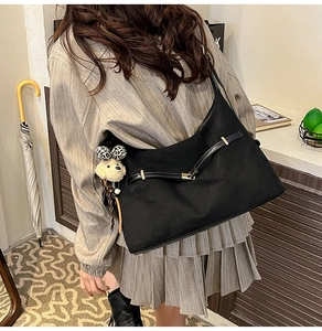 Detail of black canvas dumpling bag with leather strap and leopard print bear charm