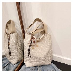 Dettaglio della borsa tote beige con cuciture a foglia e ciondolo in peluche morbido