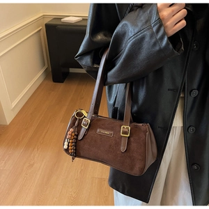 Dettaglio borsa a spalla in pelle scamosciata marrone con logo e nappe decorative