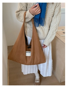Detail of brown suede tote bag featuring a toggle closure and a SEEYOU patch label