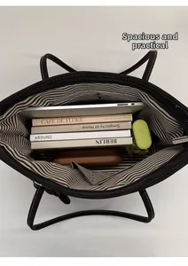Spacious interior of large black canvas tote bag with laptop, books, and zip compartment