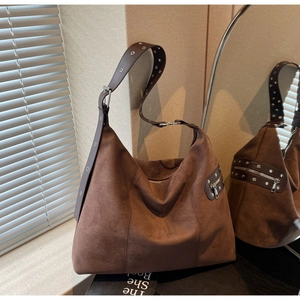 Detail of suede shoulder bag with silver rivet straps and dark brown matte finish