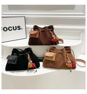 Three retro frosted bucket bags in brown and black with pom-pom charms on white display