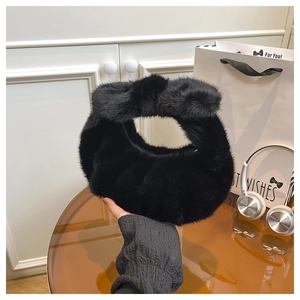 Dettaglio di borsa in finta pelliccia nera con elegante fiocco in peluche sul manico