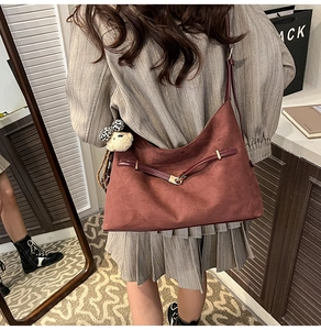 Deep burgundy suede dumpling bag with a velvet texture and cute sheep charm in use