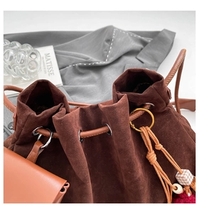 Close-up of vintage brown suede bucket bag texture with drawstring and metal ring detail