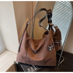 Close-up of brown suede hobo bag with wide shoulder strap and silver metal eyelet details