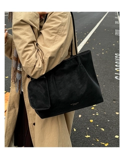 Vue détaillée d'un cabas en cuir noir avec petite pochette amovible dans un cadre d'automne
