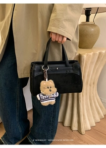 Dettaglio della borsa in pelle nera testurizzata con ciondolo a orsetto e perle
