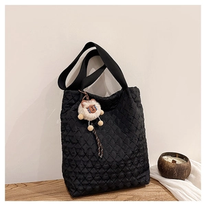 Detail of black quilted tote bag with matte texture and a plush lamb pendant charm