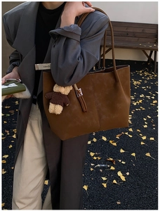 Close-up of brown suede tote bag featuring a cute bear pendant and fringe details