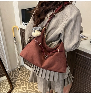 Detail of burgundy suede hobo bag with gold hardware and leopard bow bear charm