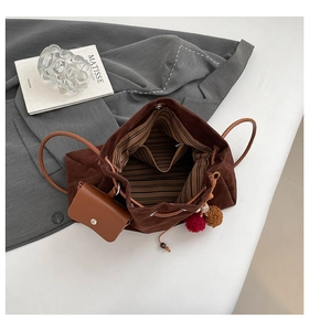 Detail view of large dark brown suede bucket bag with striped lining and mini charm