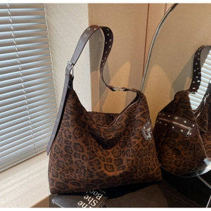 Detail of leopard print suede bag featuring silver metal rivets on dark brown leather strap