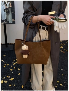 Brown faux suede tote bag with cute bear charm shown in an autumn street setting