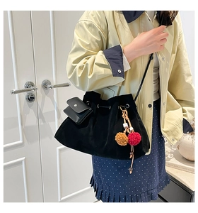 Detail of vintage black velvet bucket bag with drawstring closure and plush pendant charms