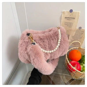 Détail du sac en fausse fourrure rose avec chaîne en perles blanches et boucles dorées