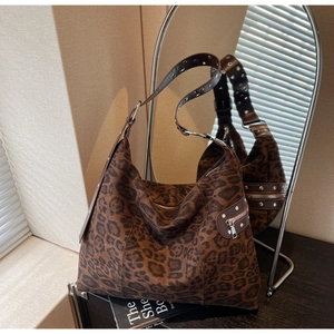 Detail of leopard print tote bag with silver rivets on the brown leather strap