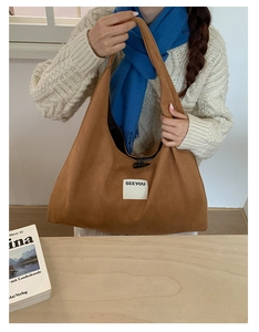 Detail of brown suede hobo bag with horn toggle closure and white square logo patch