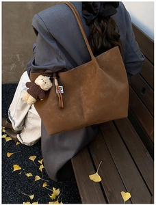 Brown faux suede tote bag with a cute bear charm shown in a cozy autumn park setting
