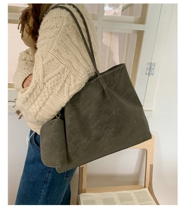 Detail view of large suede tote bag and matching pouch on a cozy autumn sweater
