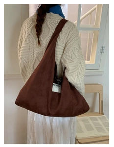 Close-up of a large brown faux suede tote bag with a white minimalist textile logo