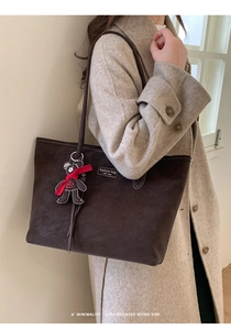 Detail of coffee brown tote bag with suede texture and cute teddy bear pendant
