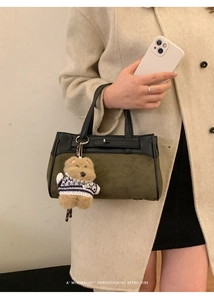 Dettaglio della borsa in pelle scamosciata verde oliva con finiture nere e ciondolo orsetto