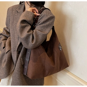 Detail of dark brown suede tote bag with wide rivet strap and metallic side zipper trim