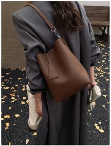 Macro detail of HOCOMU brown pebble leather texture and silver buckle on bucket bag