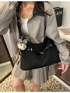 Large black dumpling-style shoulder bag with leopard bow bear charm on model