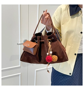 Detail of dark brown suede hobo bag with colorful pompom and mini leather pouch