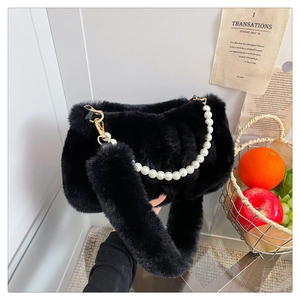 Détail du sac en fausse fourrure noire avec chaîne en perles et large bandoulière douce