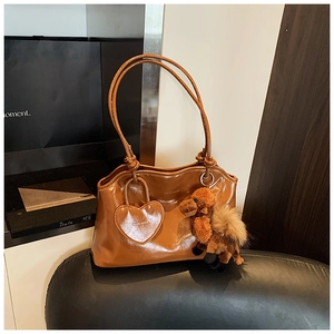 Dettaglio di una borsa a spalla in pelle lucida marrone con ciondolo a forma di cammello